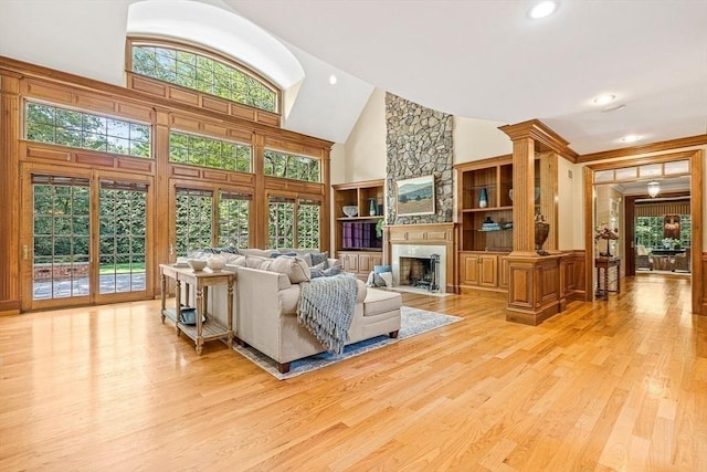 living room featuring high vaulted ceiling, a large fireplace, a healthy amount of sunlight, and wood finished floors