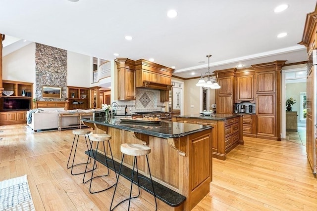 kitchen featuring tasteful backsplash, light wood-style flooring, a breakfast bar area, brown cabinets, and a center island