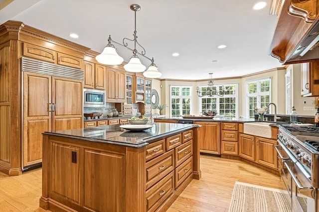 kitchen with built in appliances, a peninsula, ornamental molding, and a center island