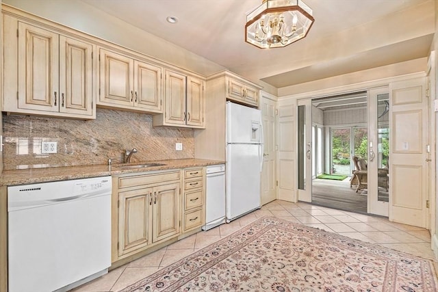 kitchen with light tile patterned floors, white appliances, a sink, decorative backsplash, and an inviting chandelier