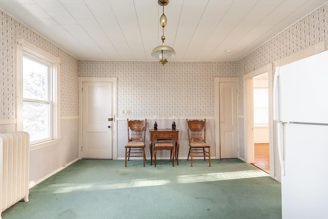 unfurnished dining area featuring wallpapered walls, radiator, carpet flooring, and a wainscoted wall