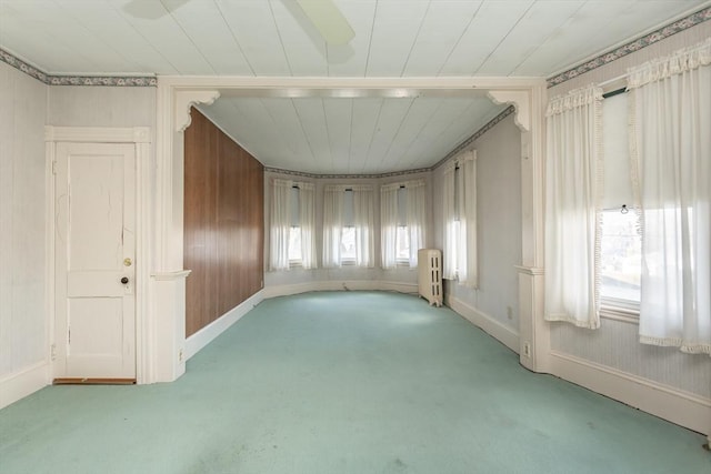 empty room featuring radiator, baseboards, and light colored carpet