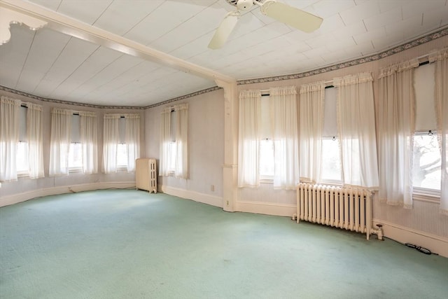 empty room with plenty of natural light, light colored carpet, and radiator heating unit