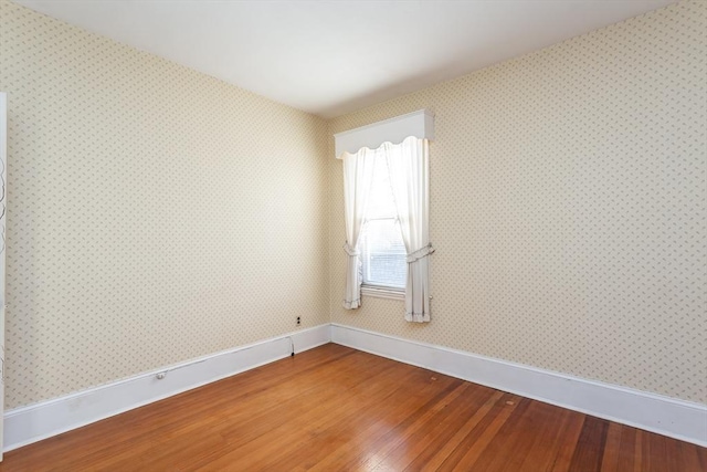 empty room with wallpapered walls, baseboards, and light wood finished floors