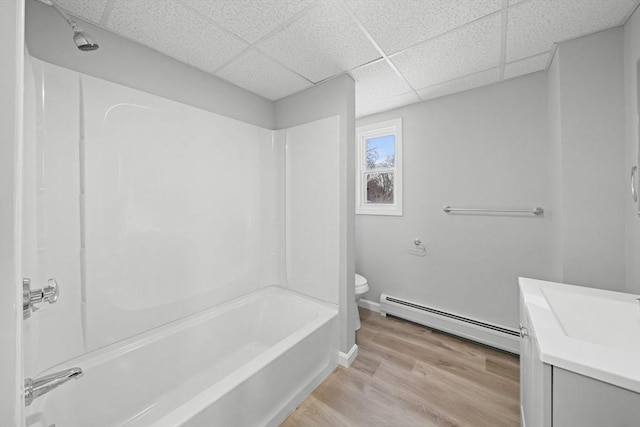 full bathroom with vanity, wood-type flooring, a drop ceiling, a baseboard radiator, and toilet