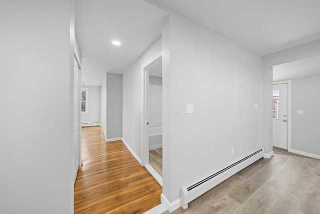 hallway with a baseboard radiator and light hardwood / wood-style flooring