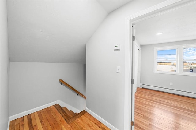 stairway with hardwood / wood-style flooring, vaulted ceiling, and a baseboard heating unit