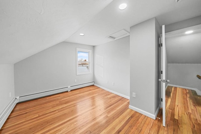 additional living space featuring a baseboard radiator, lofted ceiling, and light hardwood / wood-style flooring