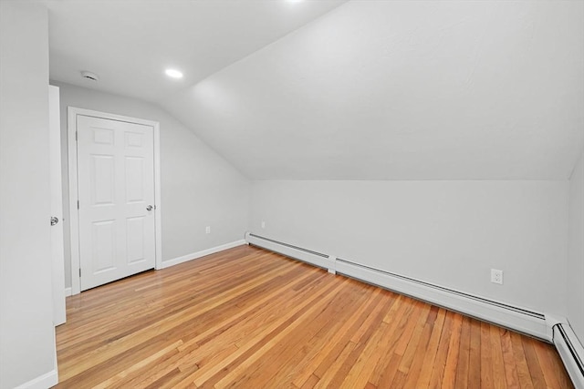 bonus room with lofted ceiling, a baseboard heating unit, and light wood-type flooring