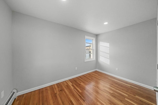 empty room with baseboard heating and wood-type flooring