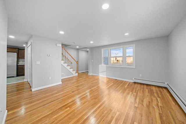 unfurnished living room with a baseboard radiator and light wood-type flooring