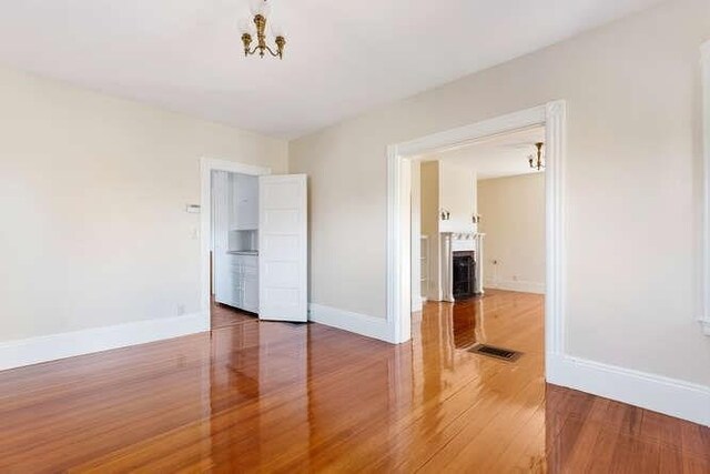 4-6 W St, Arlington, MA 02476 - unfurnished bedroom with wood finished floors, a chandelier, baseboards, and a fireplace with flush hearth