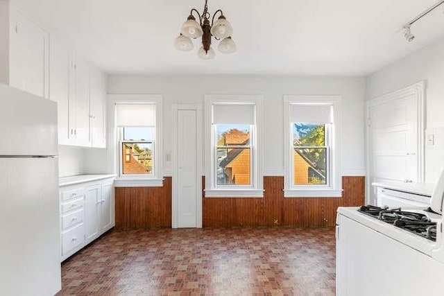 4-6 W St, Arlington, MA 02476 - kitchen with freestanding refrigerator, white range oven, a chandelier, white cabinetry, and wainscoting