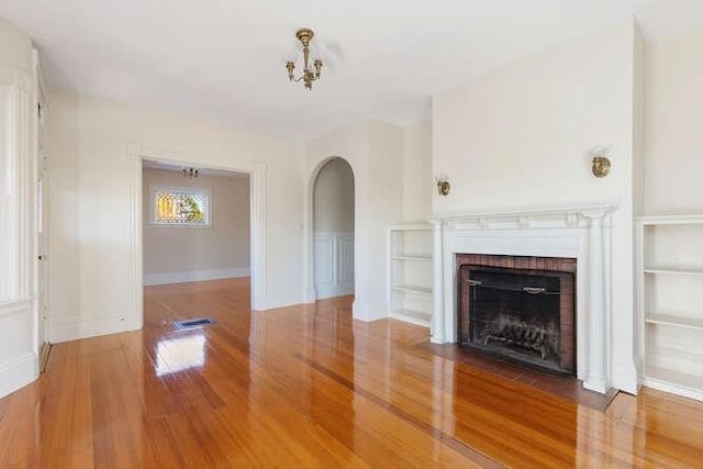 4-6 W St, Arlington, MA 02476 - unfurnished living room featuring wood finished floors, arched walkways, and a brick fireplace