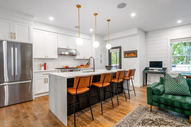16 Walker St Unit 16, Medford, MA 02155 - kitchen with freestanding refrigerator, under cabinet range hood, light countertops, light wood-style floors, and decorative backsplash