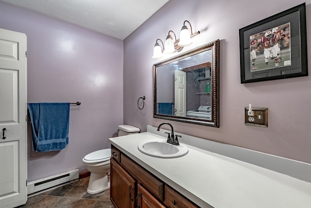 bathroom featuring toilet, tile patterned flooring, vanity, washer / dryer, and a baseboard heating unit