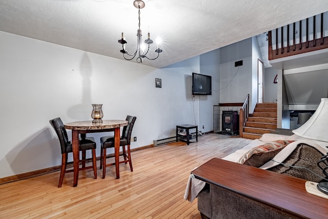 dining room featuring a textured ceiling, light hardwood / wood-style flooring, a baseboard heating unit, and a chandelier