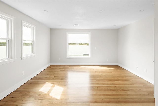 empty room featuring light wood-style flooring, visible vents, and baseboards