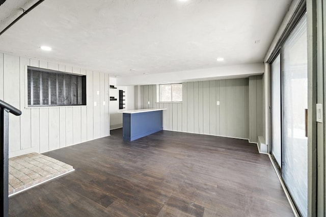 unfurnished living room with wood walls and dark wood-style floors