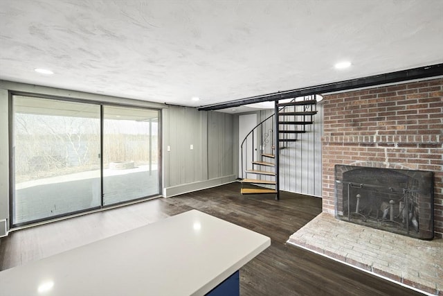 unfurnished living room featuring visible vents, baseboards, a brick fireplace, wood finished floors, and stairway
