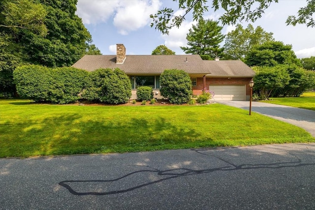 view of front of house with a garage, driveway, a front lawn, and a chimney