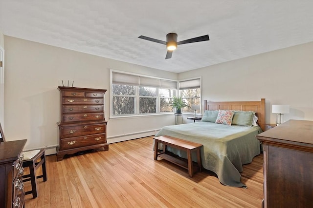 bedroom featuring light wood finished floors, baseboard heating, and a ceiling fan