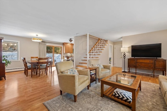 living room with stairs, light wood finished floors, and a baseboard radiator