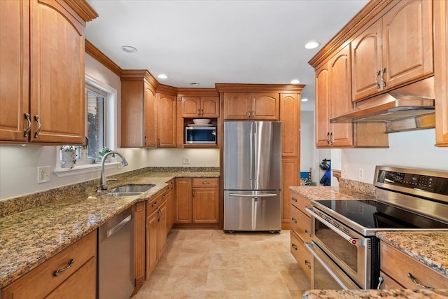 kitchen featuring light stone counters, recessed lighting, under cabinet range hood, stainless steel appliances, and a sink