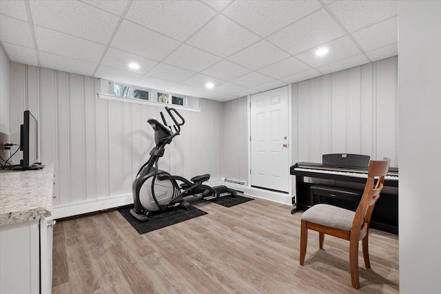 workout room with a baseboard radiator, a drop ceiling, and wood finished floors