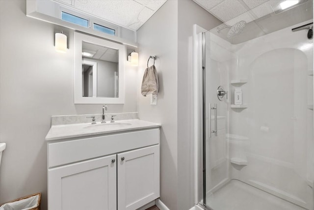 full bath featuring a stall shower, a drop ceiling, and vanity