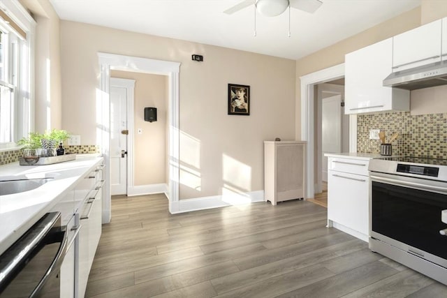 kitchen with electric range, under cabinet range hood, ceiling fan, light countertops, and light wood-style floors