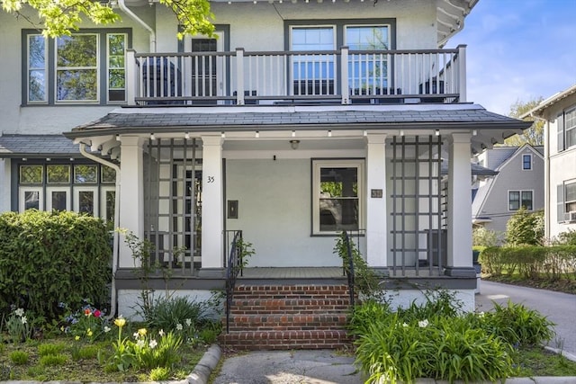 view of front of house featuring a balcony, a porch, and stucco siding