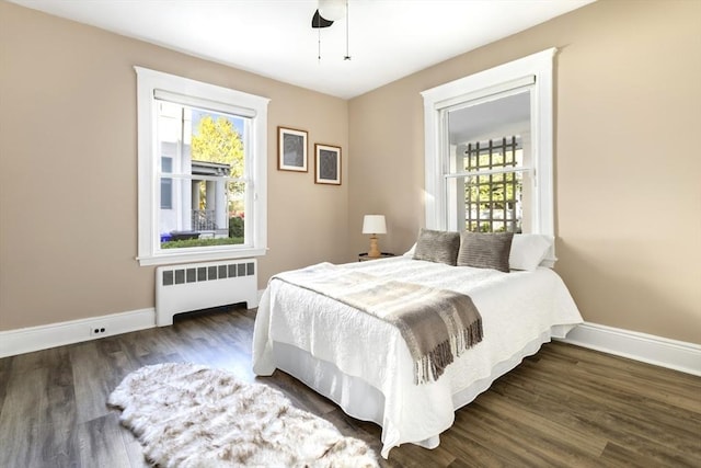 bedroom featuring radiator, baseboards, wood finished floors, and a ceiling fan
