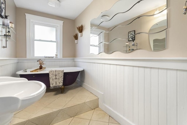bathroom featuring a wainscoted wall, a freestanding tub, tile patterned floors, and plenty of natural light