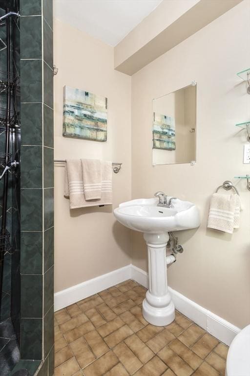bathroom featuring tiled shower, baseboards, and toilet