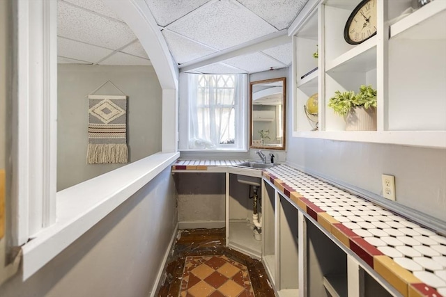 interior space featuring a sink, dark floors, and a paneled ceiling