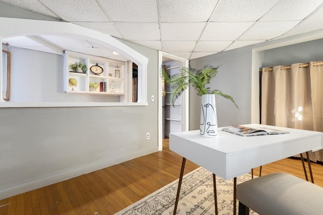 dining space with baseboards, wood finished floors, and a paneled ceiling