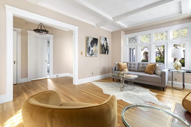 living area featuring baseboards, light wood finished floors, beam ceiling, and coffered ceiling