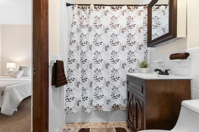 bathroom featuring vanity, toilet, and tile walls