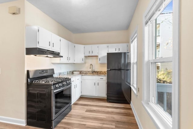 kitchen featuring light hardwood / wood-style floors, white cabinetry, a healthy amount of sunlight, and black appliances