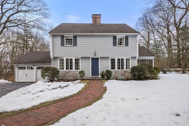 view of front of home with driveway, a chimney, and an attached garage