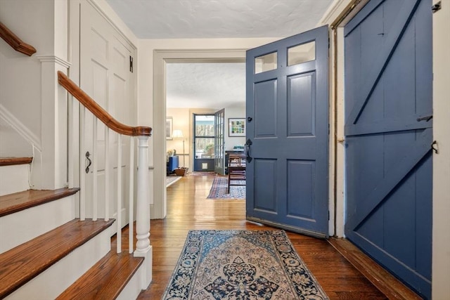 foyer entrance featuring a barn door, stairway, and dark wood finished floors