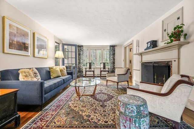 living room with a textured ceiling, a fireplace, and wood finished floors