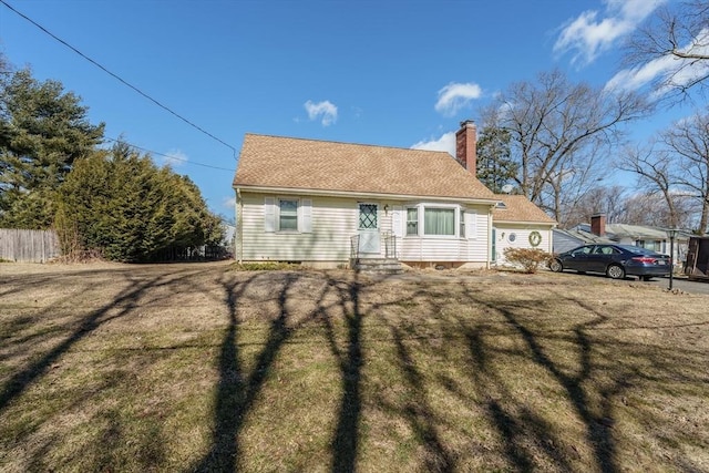 view of front of property with a shingled roof, a chimney, a front yard, and fence