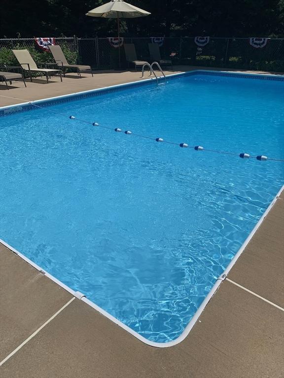 community pool with a patio area and fence