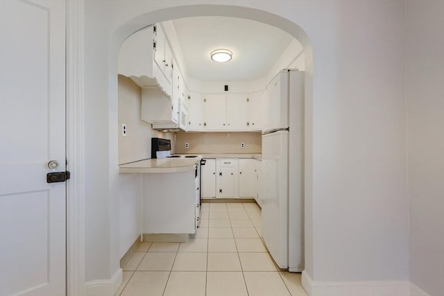 kitchen featuring light countertops, arched walkways, baseboards, and white appliances