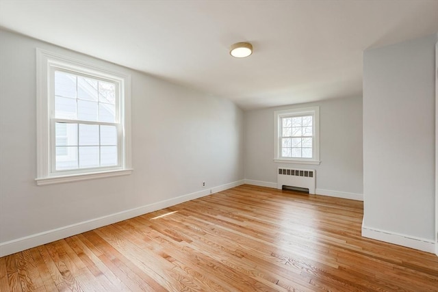 spare room with light wood-style floors, baseboards, and radiator heating unit