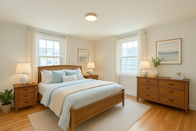 bedroom featuring baseboards, light wood-style flooring, and multiple windows