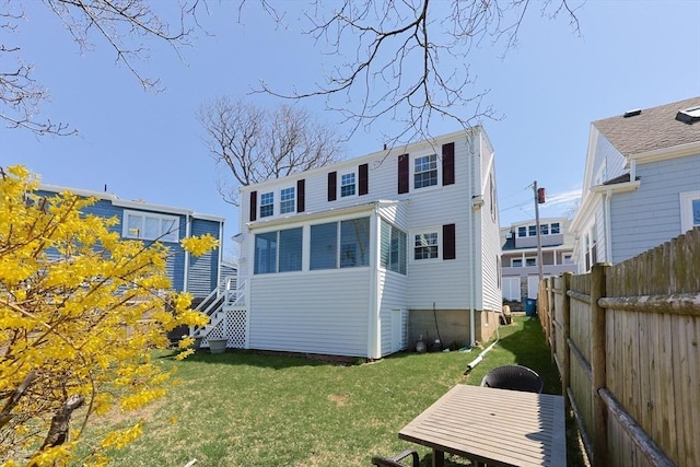 rear view of property featuring a lawn and fence