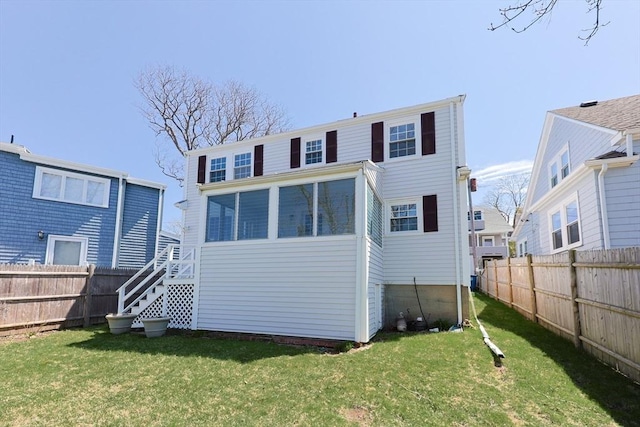 rear view of house with stairway, a lawn, and fence